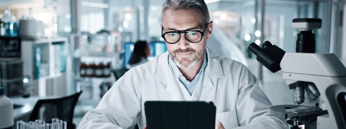Scientist analyzing data on tablet in modern laboratory with microscope and advanced research equipment